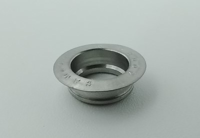 A metallic Airloc Grommet with a circular design and a central hole, placed on a plain light gray surface.