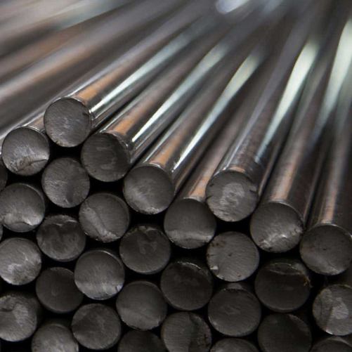 Close-up of stacked 4130 steel rods, showing their cylindrical shape and metallic sheen. The rods are arranged horizontally, displaying their smooth, reflective surfaces.