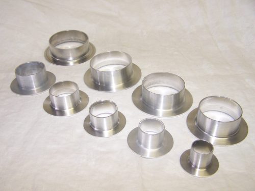 Various sizes of Aeroduct flanges are displayed, made of shiny metal. The flanges have a cylindrical shape with a wider base and a smaller opening at the top, arranged in a row on a light background.
