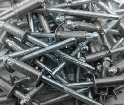 A pile of Cherry Q Rivet BS Series fasteners in metallic silver, showcasing their threaded shafts and round heads.