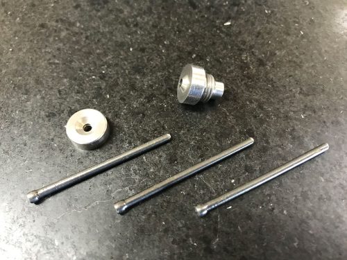 The image shows a 120º dimpling tool set on a dark surface. It includes a round metal die, a threaded tool head, and three metal rods, each with a ball end, arranged neatly.