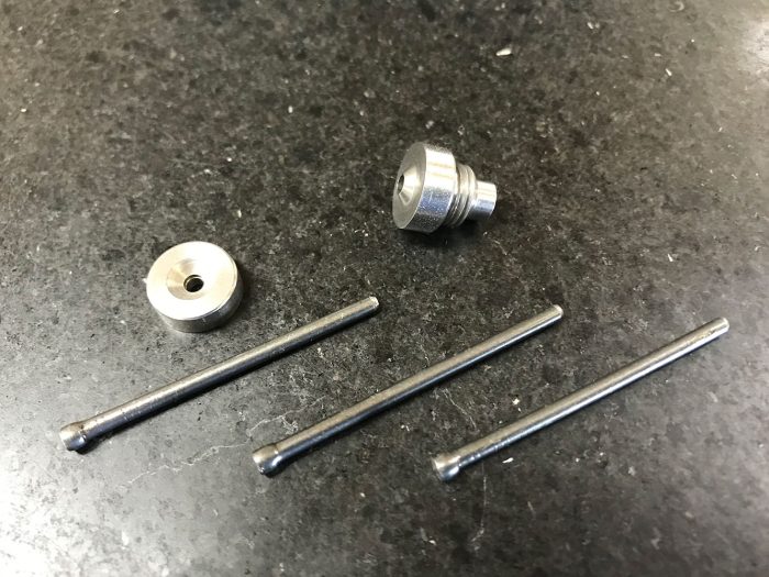 The image shows a 120º dimpling tool set on a dark surface. It includes a round metal die, a threaded tool head, and three metal rods, each with a ball end, arranged neatly.