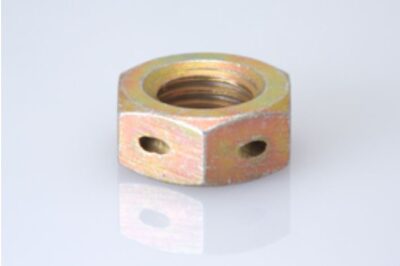 The image shows a metal drilled jam nut with a hexagonal shape and two visible holes on its sides. The nut is placed on a reflective white surface, highlighting its metallic finish and threaded interior.