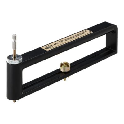 A black metal hole cutter with an adjustable frame and a central cutting bit. The tool features a labeled plate on top and is designed for precision cutting in various materials.
