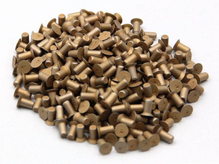 A pile of MS20426 Countersunk 100° Solid Rivets, showing their flat, angled heads and cylindrical bodies, arranged on a white surface.