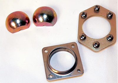 Two spherical grommets are shown alongside a hexagonal and a square metal bracket with circular openings, all on a white background.