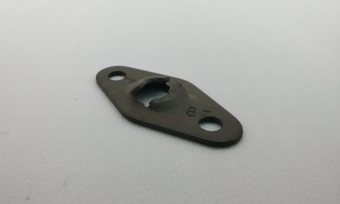 Image of an "Anchor Type Speed Nut Flat," a metal fastener with a central raised section and two holes on either end, lying on a plain surface.