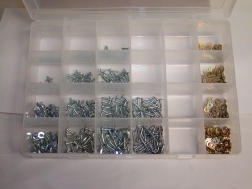 A clear plastic storage box containing a variety of sheet metal screws, organized into compartments. The screws are predominantly silver, with some gold-colored ones visible. The box is open, displaying the contents neatly arranged.
