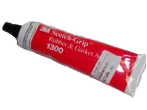 A red tube of 3M Scotch-Grip 1300 Rubber & Gasket Adhesive with a black cap, laying on its side.