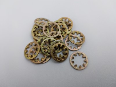 A pile of metallic split lock washers with serrated edges arranged on a plain surface.