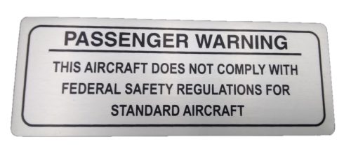 Sign with the title "Passenger Warning – ELSA" reads: "Passenger Warning: This aircraft does not comply with federal safety regulations for standard aircraft."