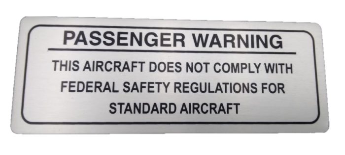 Sign with the title "Passenger Warning – ELSA" reads: "Passenger Warning: This aircraft does not comply with federal safety regulations for standard aircraft."