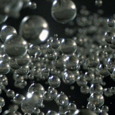 Floating glass bubbles against a dark background, reflecting light and creating a shimmering effect.