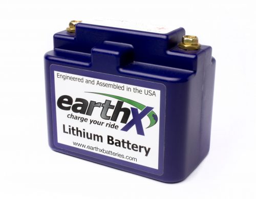 Blue EarthX lithium battery with brass terminals, labeled "Engineered and Assembled in the USA." The front label reads "EarthX, charge your ride, Lithium Battery" with the website www.earthxbatteries.com.