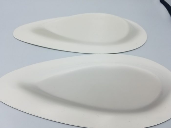 Two white, teardrop-shaped Powerburst Mounts on a flat surface, designed for stability and support.