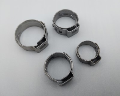 Four metallic stepless ear clamps of varying sizes are arranged on a plain surface.