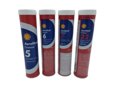 Four red and white AeroShell Grease tubes are standing upright. Each tube is labeled with different numbers: 5, 6, 7, and 22, indicating various types of grease. The Shell logo is visible on each tube.