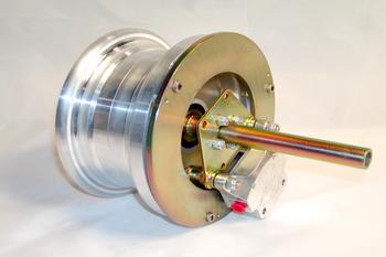 A metallic mechanical component with a cylindrical body and a protruding rod, featuring bolts and a small red knob. The component is placed on a white surface, highlighting its shiny metal finish.