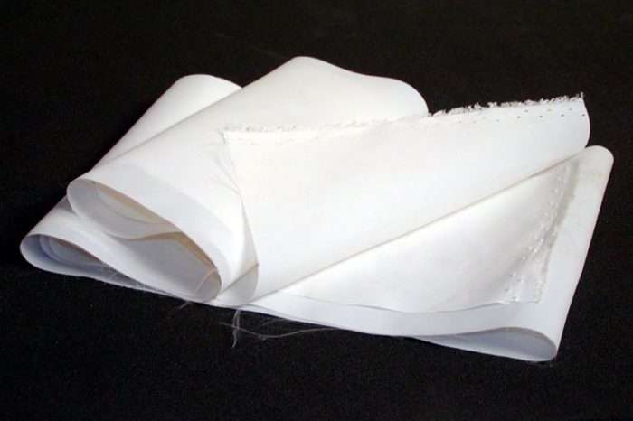 A piece of white, folded paper with frayed edges lies on a dark surface.