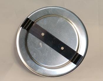A round metal lid with a black handle across the top, featuring two small holes. The lid is set against a plain, light-colored background.