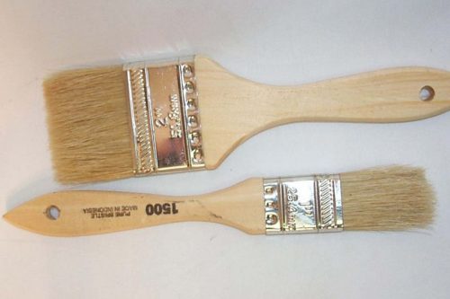 Two paintbrushes with wooden handles and light bristles are placed side by side on a white background. The larger brush is above the smaller one, both featuring metal ferrules and holes at the handle ends for hanging.