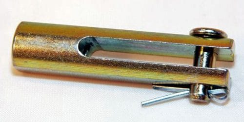 A metal clevis pin with a cylindrical body, a vertical slot, and a removable cotter pin inserted at the end, resting on a white surface.