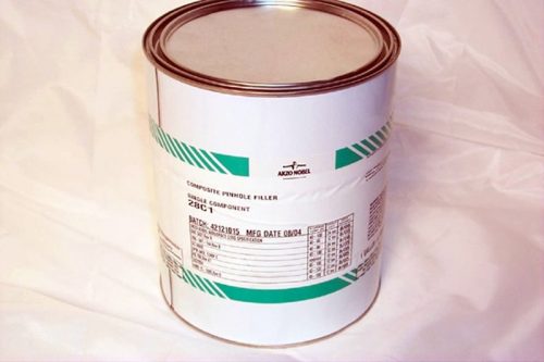 A large, sealed metal can with a white label featuring green stripes and text, placed on a white surface.