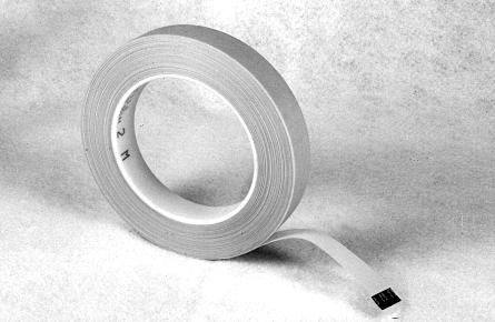 A roll of white adhesive tape with a loose end extending outward, lying on a textured surface.