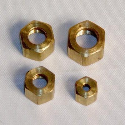 Four brass hex nuts of varying sizes arranged on a white surface.
