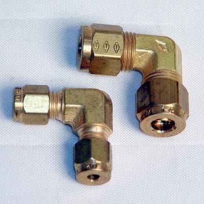 Two brass elbow pipe fittings with threaded ends are placed on a white surface.