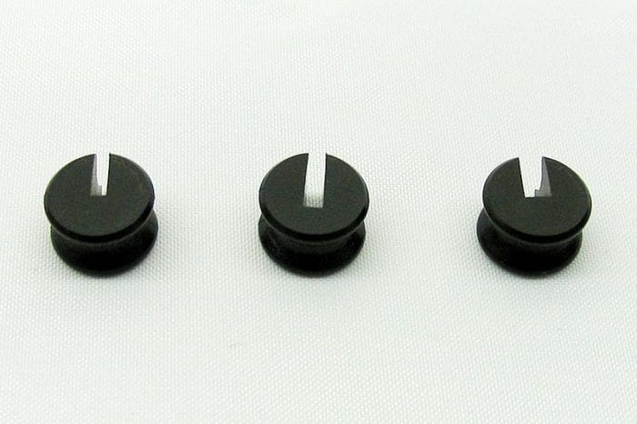 Three black circular objects with vertical slits are lined up horizontally on a white background.