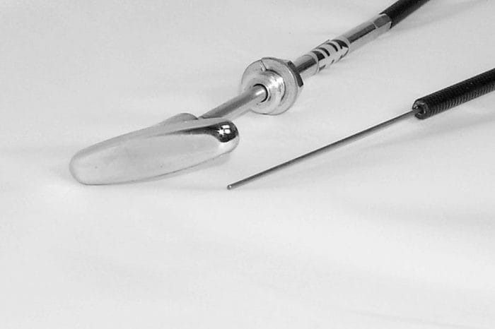Two surgical instruments are shown on a white surface: a metal orthopedic reamer with a curved blade and a long, thin guide wire.