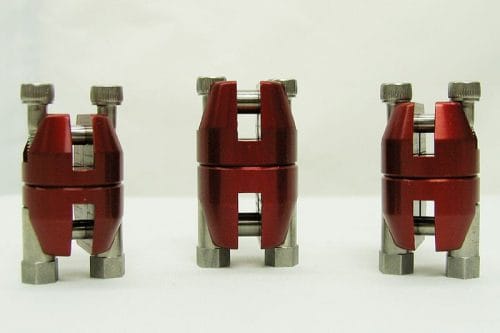 Three red and silver mechanical clamps are arranged in a row against a plain background. Each clamp has a central red section with metallic components on the top and bottom.