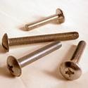 Four metal screws of varying lengths and types are arranged on a light surface.