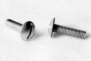Two slotted screws lying on a white surface, one facing up and the other on its side, showing the threaded shaft.