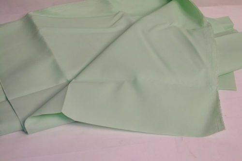 A light green fabric is laid out flat with slight folds and creases visible. The texture appears smooth and soft.