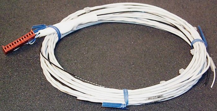 A coiled white wire with blue and red connectors on a dark surface.