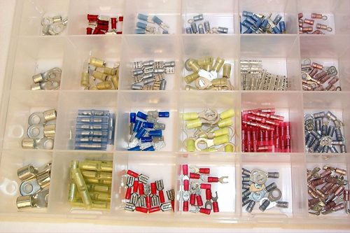 A plastic organizer with multiple compartments, each containing different types of electrical connectors in various colors, including red, blue, yellow, and silver.