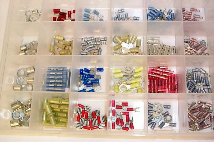 A plastic organizer with multiple compartments, each containing different types of electrical connectors in various colors, including red, blue, yellow, and silver.