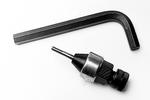 An L-shaped hex key and a drill chuck with a drill bit attached are placed on a white surface.