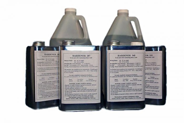 Five containers of photographic chemicals with labeled instructions, including two large jugs and three smaller bottles, are arranged in a row against a white background.