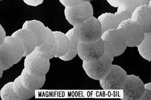 Magnified model of Cab-O-Sil, showing a chain of spherical particles connected in a strand-like formation against a dark background.