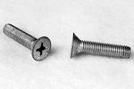 Two metal screws on a light surface, one lying flat showing a Phillips head and the other upright displaying a flat, tapered end.