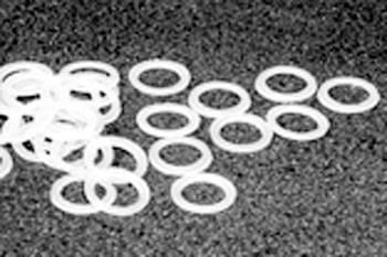 White circular rubber bands scattered on a dark textured surface.