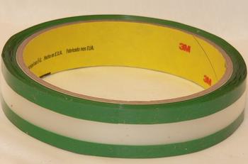 A roll of green and white adhesive tape with a yellow inner core, displaying the 3M logo. The tape is coiled neatly on a plain background.