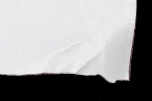 A piece of torn white paper with jagged edges against a black background.