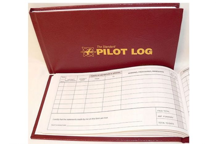 Red pilot logbook with gold lettering on the cover, open to show lined pages for recording flight details.