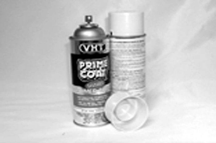 Two spray cans are shown, one labeled "VHT Prime Coat" with its cap off, and the other is a plain cylinder with the cap beside it. The background is plain and the image is in black and white.