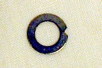 A small, dark metal split washer on a light textured surface.