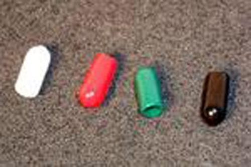 Four capsules in a row on a textured surface: white, red, green, and black.
